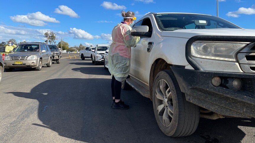 A woman in protective clothing speaks to a passenger of a four wheel drive vehicle 
