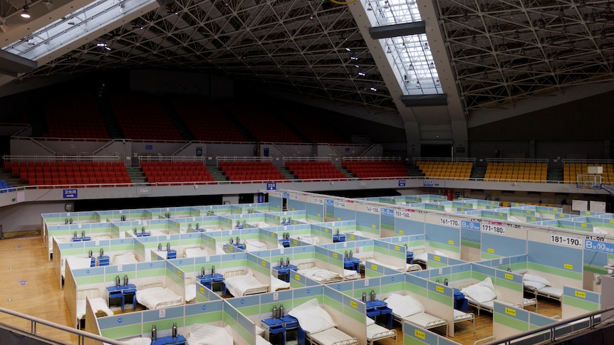 Dozens of beds set up in a stadium.