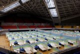Dozens of beds set up in a stadium.