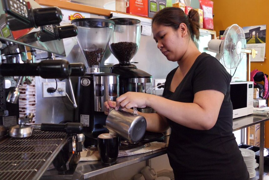 A lady making a cup of coffee.