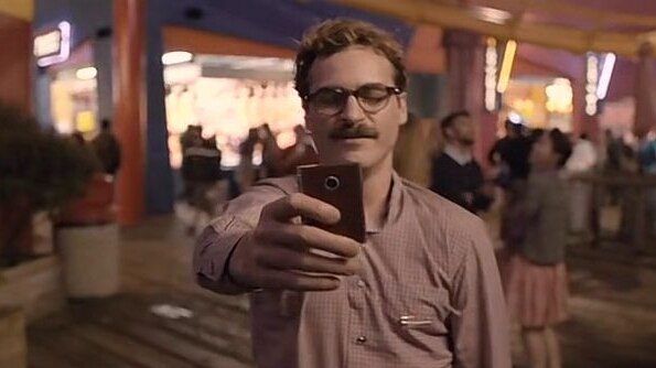 A  man with a moustache holds up a phone during a video conferencing date