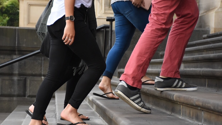 Four pairs of feet walking up stairs.