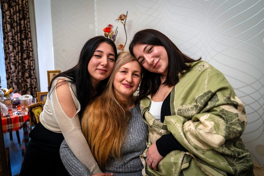 Three women hugging, and smiling at the camera