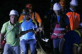 Rescuers carry the body of a victim at night.