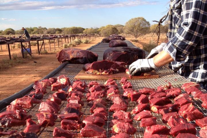 A Western Australian pastoralist cuts up chunks of horse meat to make poison baits for wild dogs.