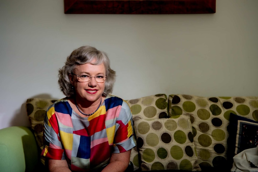 A woman in a colourful top sitting on a couch