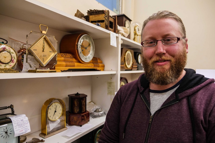 Picture of a man standing in front of some clocks