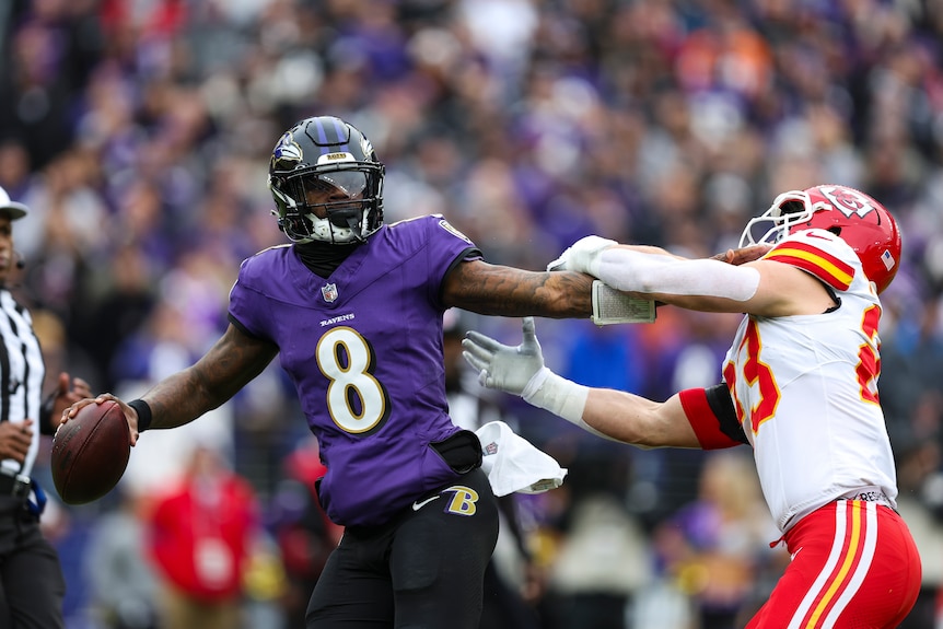 Baltimore Ravens quarterback Lamar Jackson fends off a Kansas City defender.