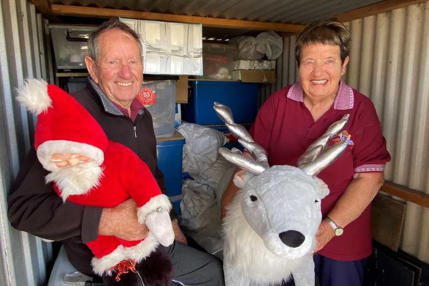 Elderly man holding a toy santa on left with woman on right holding a reindeer, both smiling 
