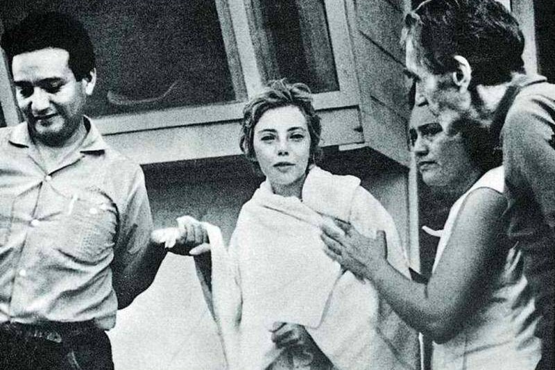 A black and white photo of a girl wrapped in a towel surrounded by adults