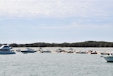 People, boats, and tarps on a strip of beach on the northern tip of South Stradbroke Island.