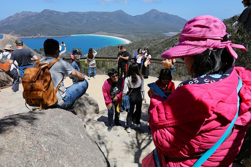 Tourists take photos from the Wineglass Bay lookout