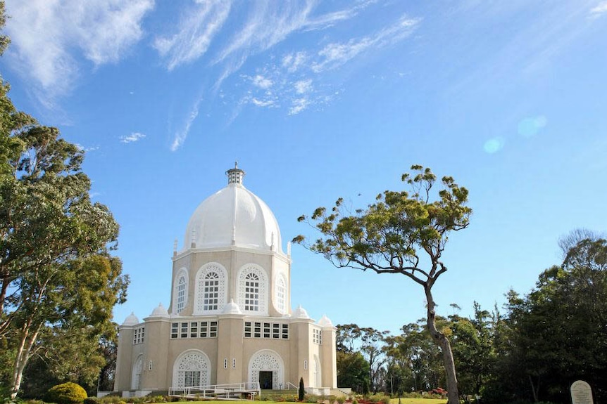 A view from above a grand, white, domed structure surrounded by garden.