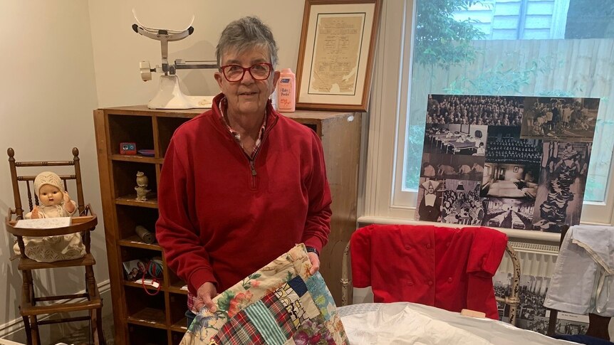 A woman holds a patchwork quilt