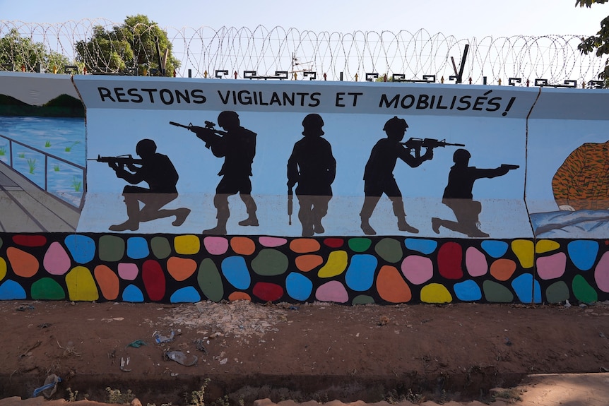 A mural with silhouettes of soldiers holding guns, above it says 'restons vigilants et mobilisés!'. 