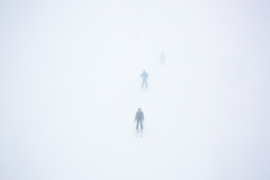 Skiers emerge out of the mist.