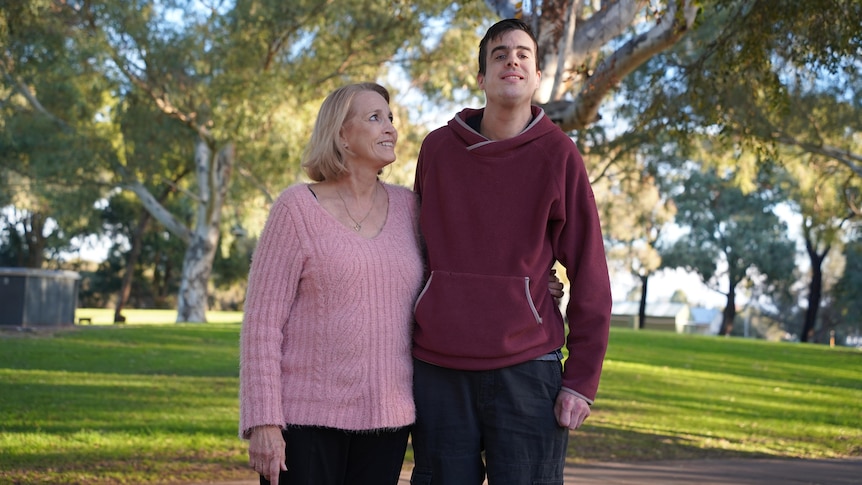 Janette and Ryan standing in a park with their arms around each other.