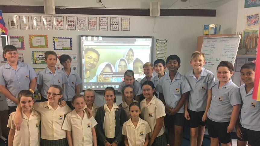 Australian students smiles with a screen on the wall showing students in Indonesia
