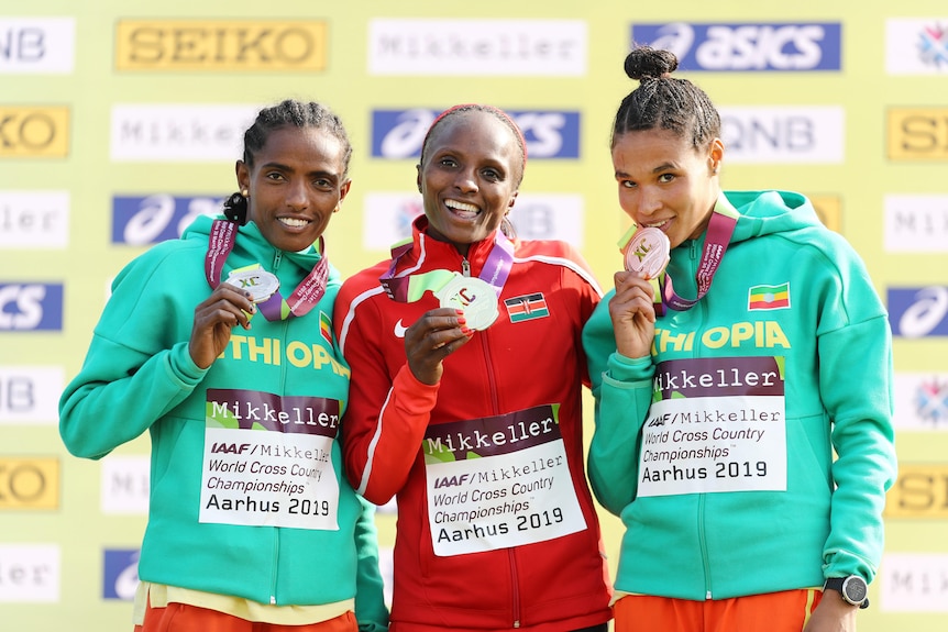 Three athletes stand with their medals after the women's senior final at the 2019 World Athletics Cross Country Championships.