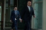 Peter Dutton looking at the camera as he strides through Parliament House.