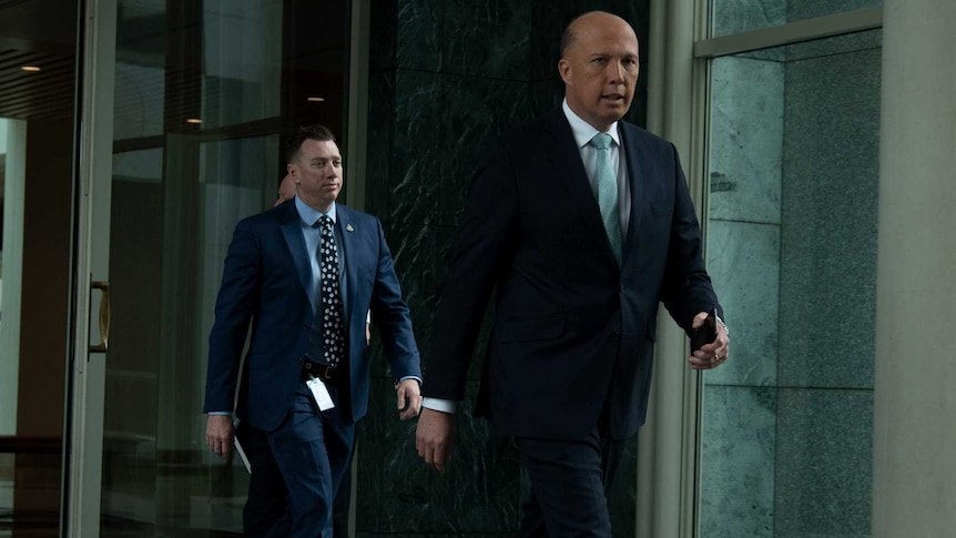 Peter Dutton looking at the camera as he strides through Parliament House.