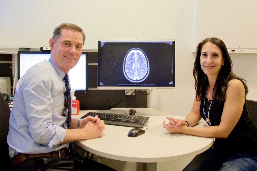 Dr Moore with Ms Zorbalas, with a brain scan in the background.