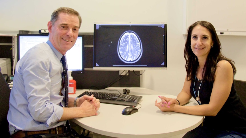 Dr Moore with Ms Zorbalas, with a brain scan in the background.