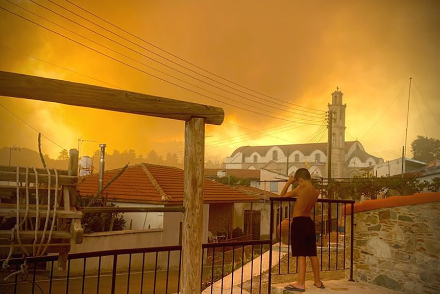 A raging fire is seen burning behind the Ora village skyline