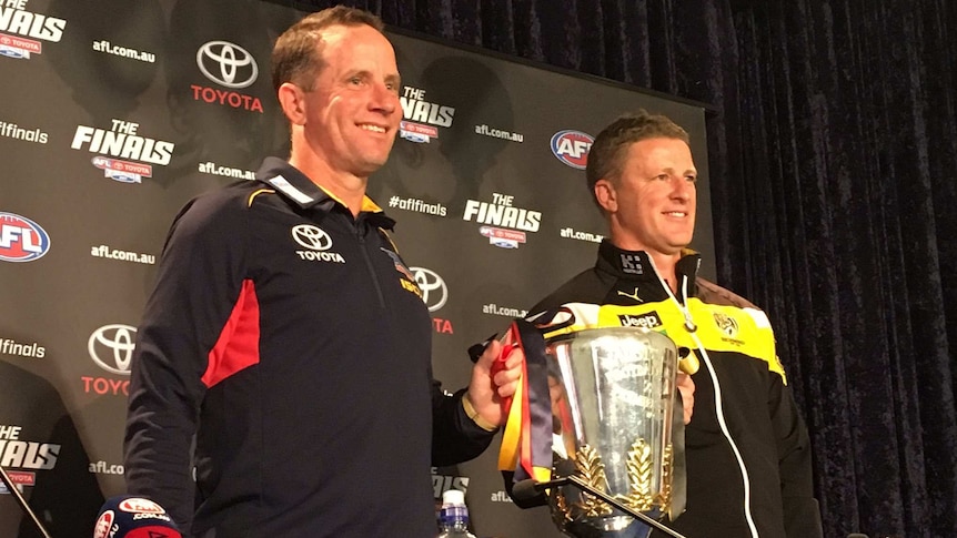 Don Pyke and Damien Hardwick smile while holding up the premiership cup.