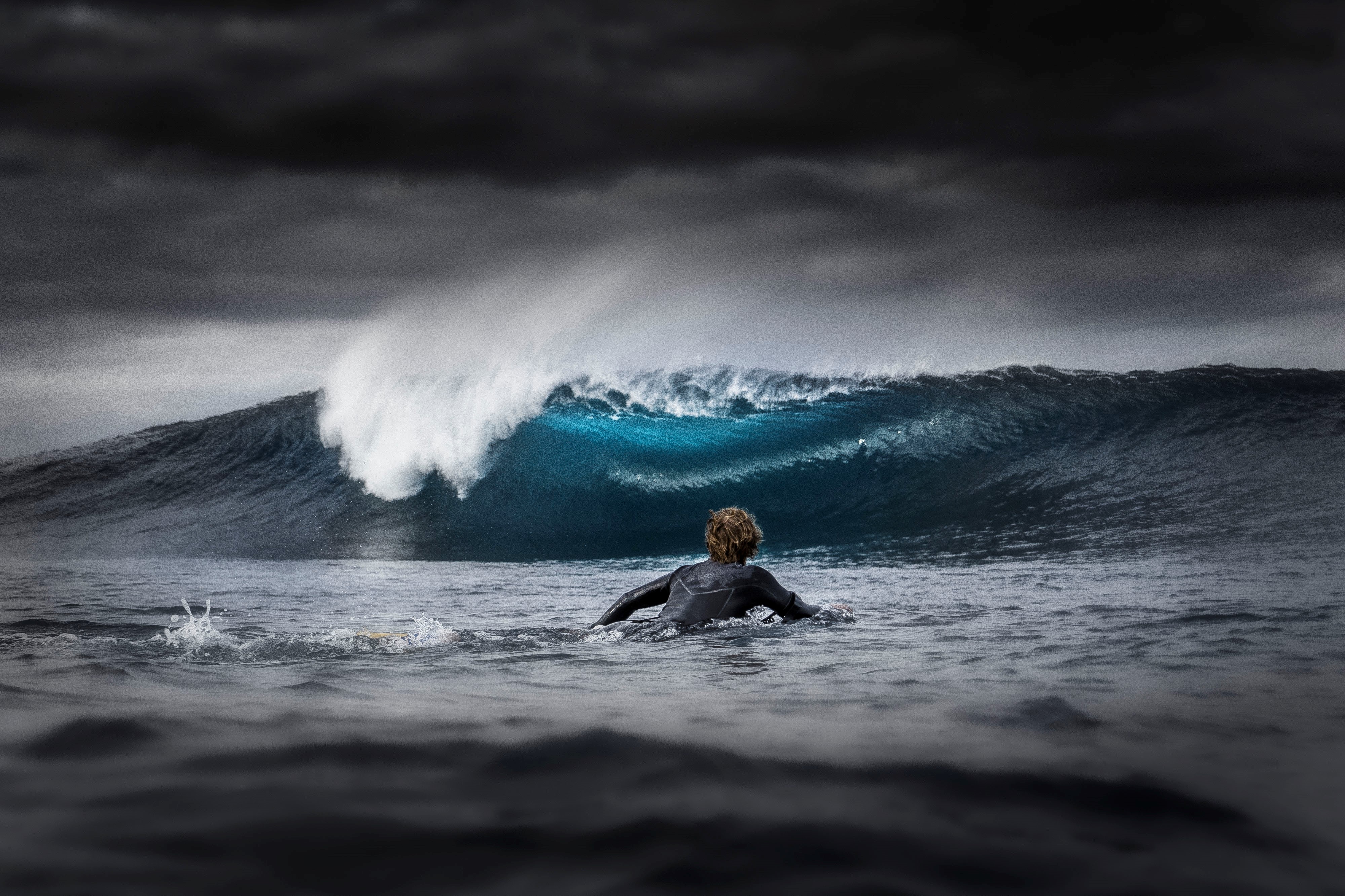 A surfer paddles towards a breaking wave