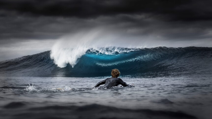 A surfer paddles towards a breaking wave