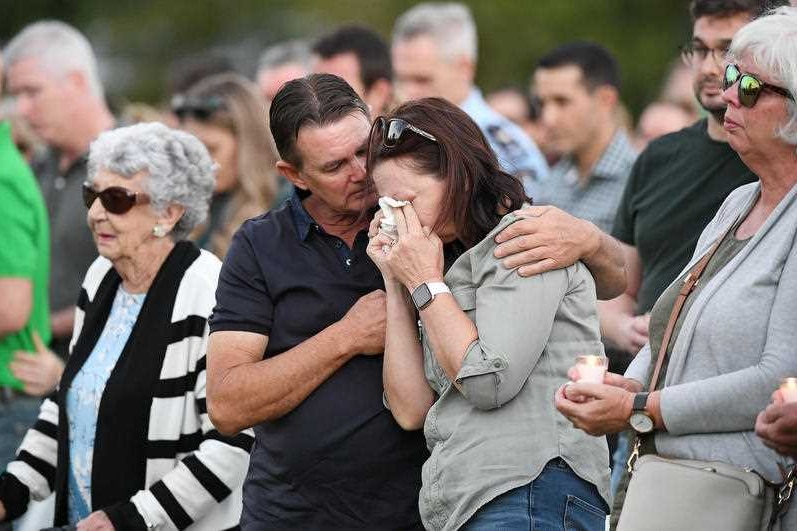A man consoles a woman who is crying in the crowd at a community vigil.