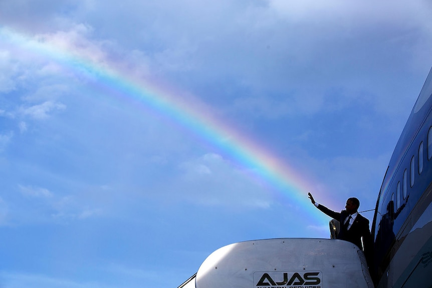 President Barack Obama waves from Air Force One with a rainbow behind him