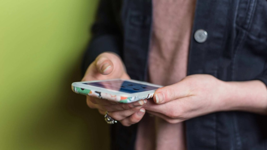 A woman holds a smartphone.