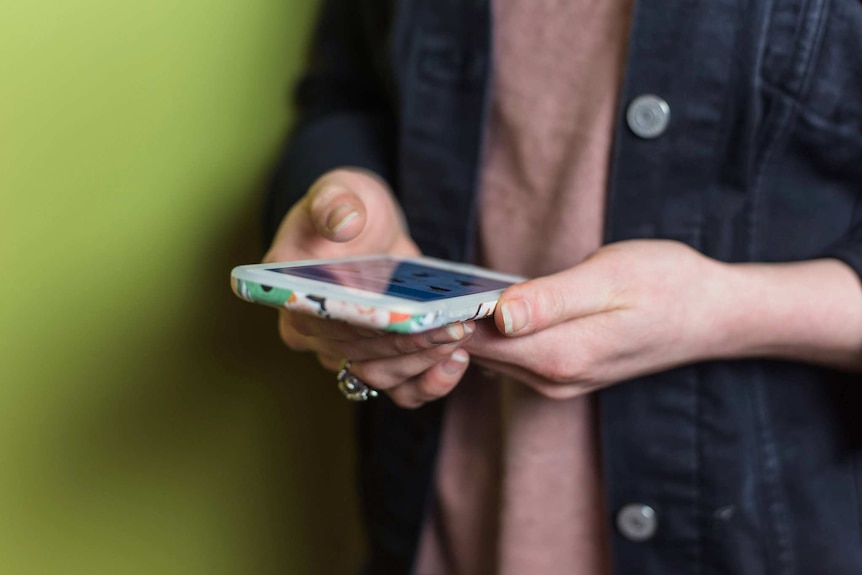 A woman holds a smartphone.