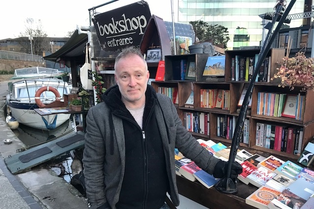 Co-owner of the floating bookshop Paddy Screech stands at entrance of store.