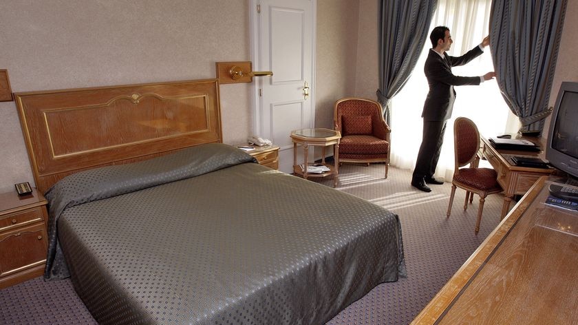 Hotel staff member adjusts the curtain in a hotel room