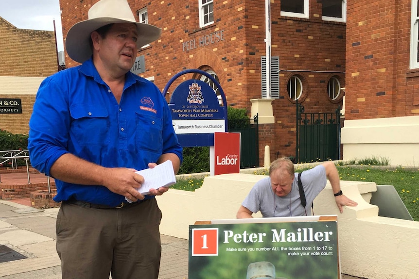 Candidate Peter Mailler hands out flyers in Armidale near a sign reading: 'get a better deal'