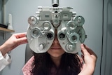 An optometrist adjusts a machine over a woman's face