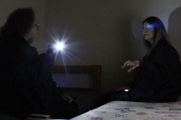 Two tour guides sit in one of the cells and try to connect with ghosts with the use of a spirit box. 