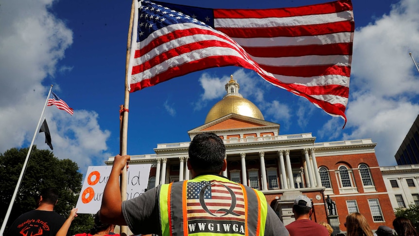 A man wearing a QAnon vest attends a rally against mandatory flu vaccinations in Massachusetts on August 30, 2020.