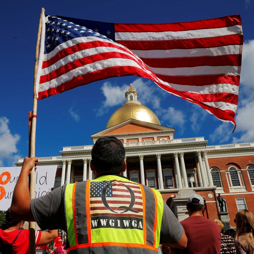 A man wearing a QAnon vest attends a rally against mandatory flu vaccinations in Massachusetts on August 30, 2020.