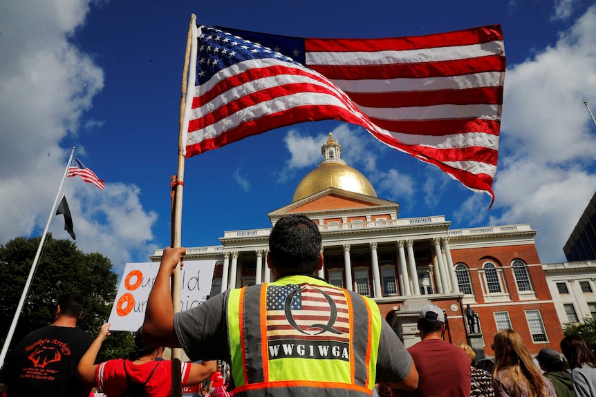 A man wearing a QAnon vest attends a rally against mandatory flu vaccinations in Massachusetts on August 30, 2020.