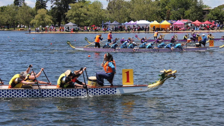 Rowing boats with the design of a dragon competing in a race on a lake.