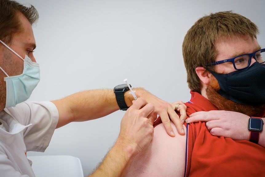 Pharmacist gives a young man a needle in the arm