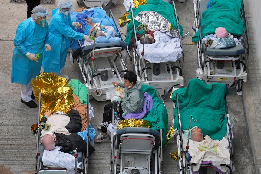 Patients lie on hospital beds as they wait at a temporary holding area outside Caritas Medical Centre.