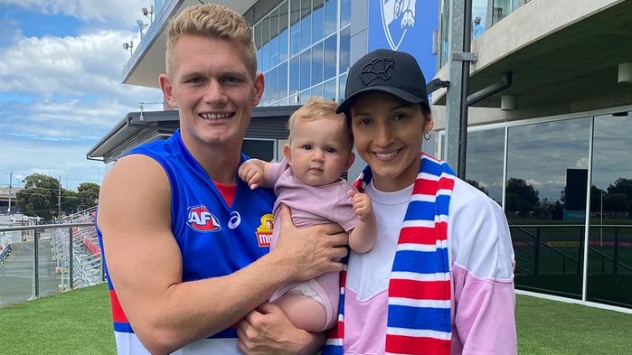 An AFL player and his family are dressed in his new club colours outside the team headquarters.