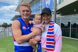An AFL player and his family are dressed in his new club colours outside the team headquarters.
