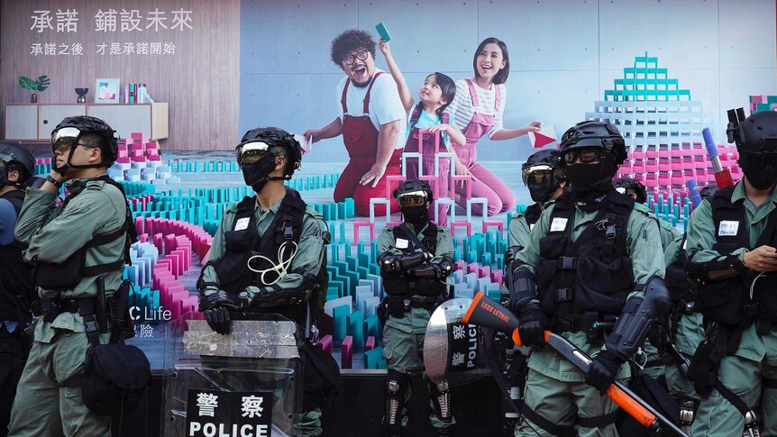 Police officers in riot gear gather in front of a billboard during an anti-government protest in Hong Kong.