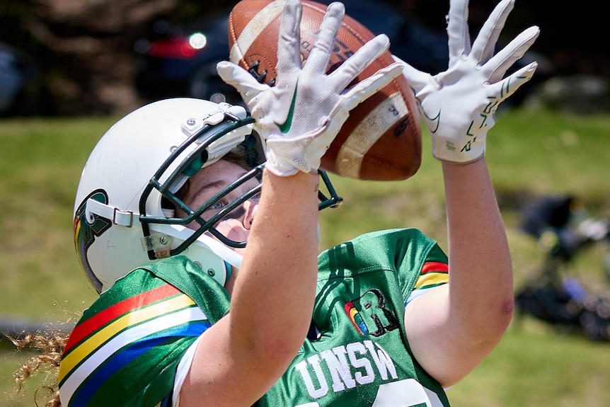 A women's gridiron player goes to catch the ball